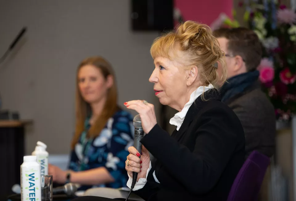 Woman with microphone speaking as a man and woman look on