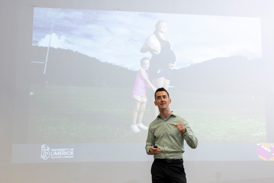 Man presenting with image of woman and girl projected onto screen in the background