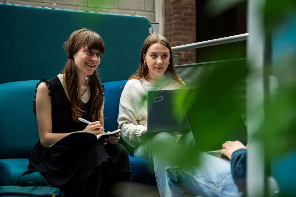 two female students studying and smiling on a couch