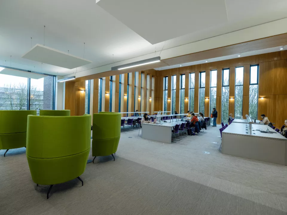 Study area in the library with large tables and big green chairs