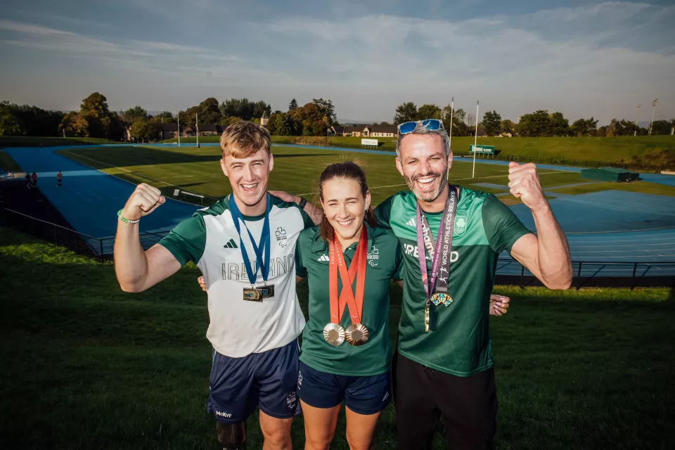 two males with a female in the middle with a running track behind them